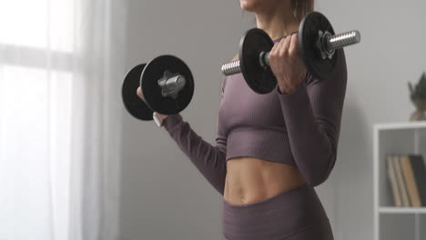 slender-sportswoman-is-training-with-dumbbells-at-homedetails-of-sporty-body-fitness-and-healthy-lifestyle-lifting-weights-for-good-shape